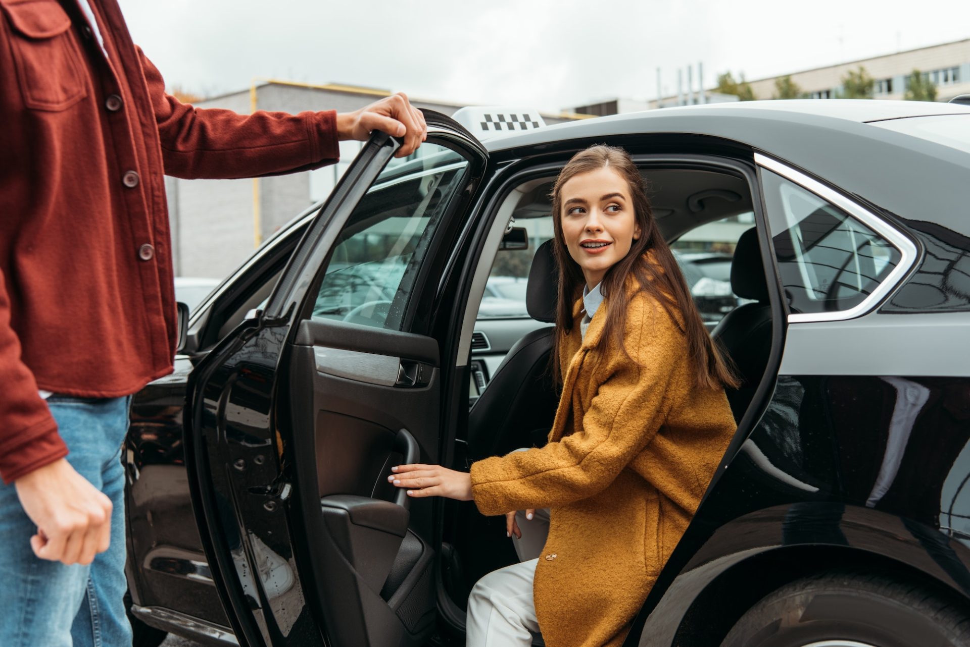 Taxi driver opening car door for smiling woman