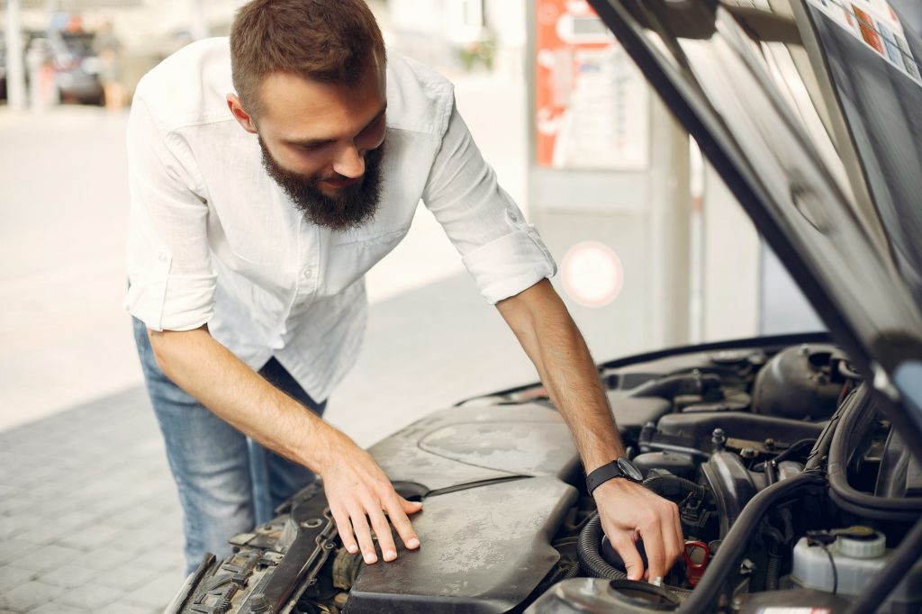 Handsome man checks the engine in his car