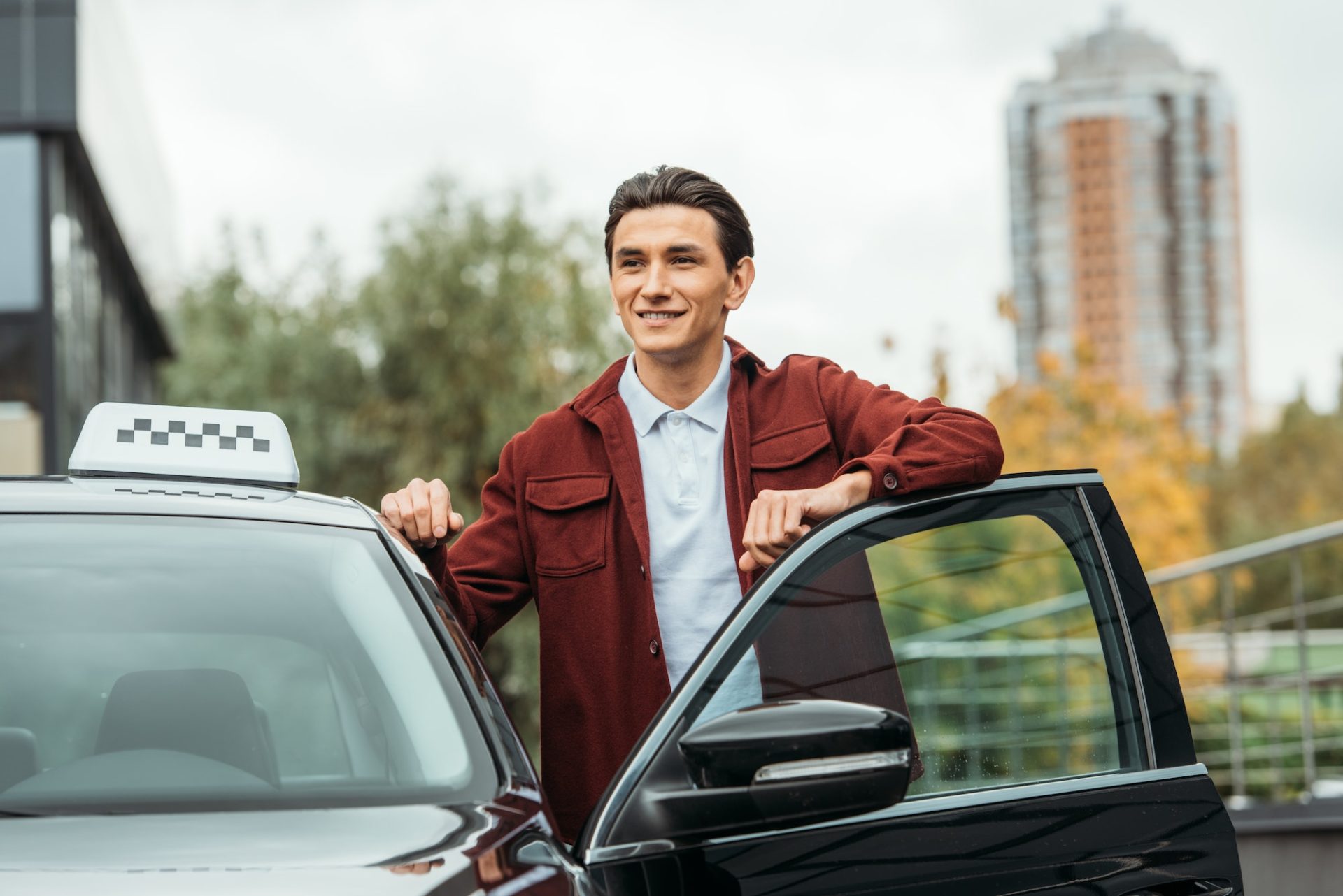 Smiling taxi driver beside open car door